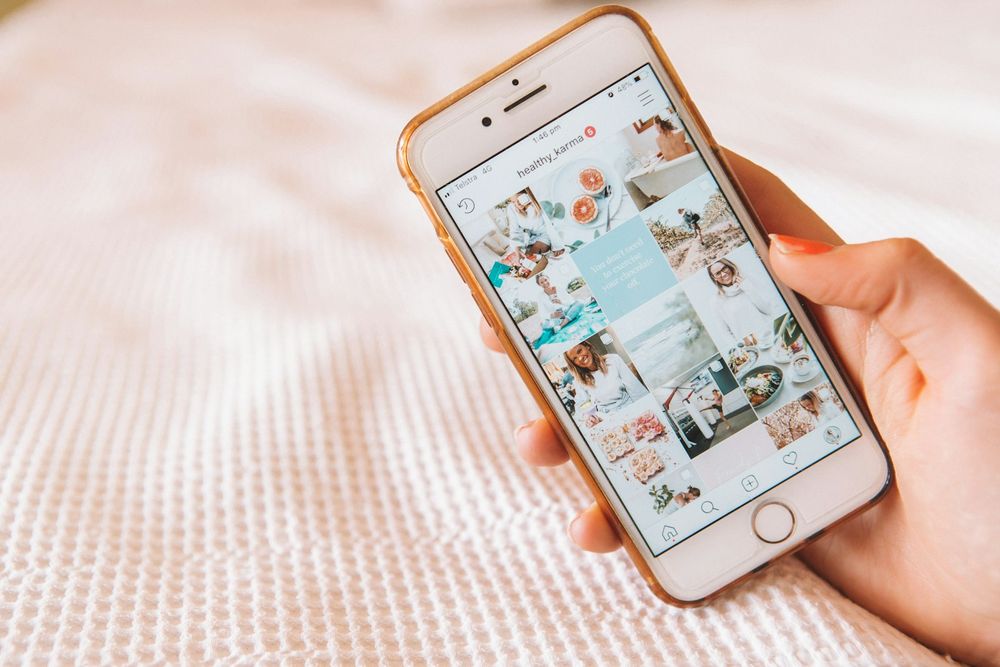 A hand scrolling a social media feed of wellness photos on a phone.